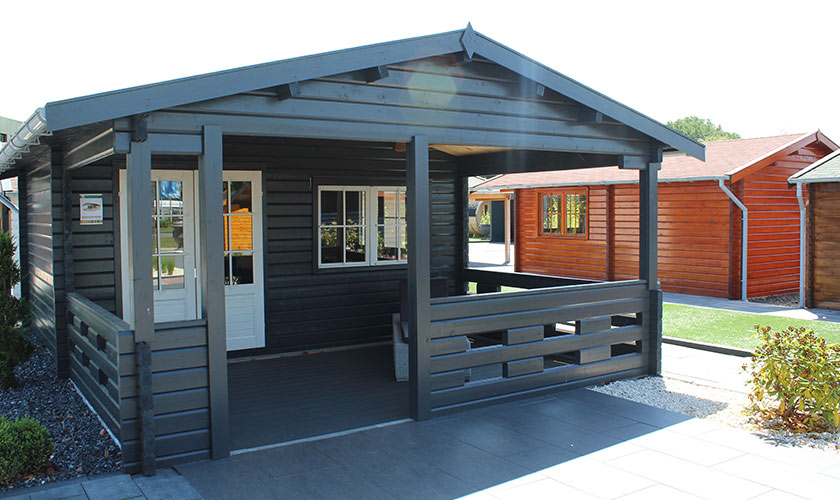 Ein modernes, schwarzes Gartenhaus mit Veranda und weißen Details bei sonnigem Wetter.